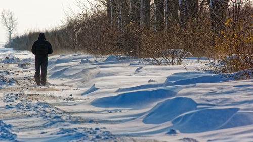 Rear view of man standing on snow covered land