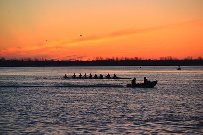 Silhouette boats in sea against orange sky