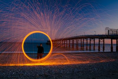 Man standing by wire wool at beach against sky