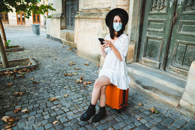 Woman holding umbrella while standing on footpath