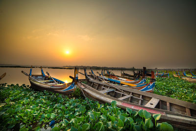 Boats moored on sea against sky during sunset