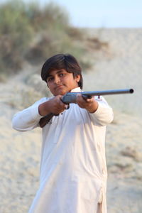 Boy using rifle while standing outdoors