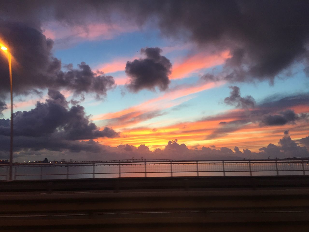 sunset, sky, cloud - sky, orange color, railing, scenics, beauty in nature, tranquility, tranquil scene, cloudy, water, dramatic sky, nature, idyllic, silhouette, fence, cloud, weather, outdoors, atmospheric mood