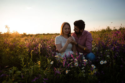 Young woman on purple flowering plants on field against sky