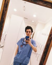 Young man using mobile phone while standing on ceiling