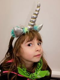 Portrait of cute girl in costume sitting against wall at home