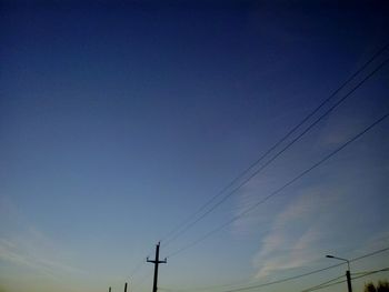 Low angle view of electricity pylon against blue sky