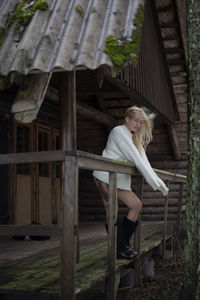 Portrait of young woman sitting on wooden wall