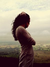 Woman looking at scenic view of landscape against cloudy sky