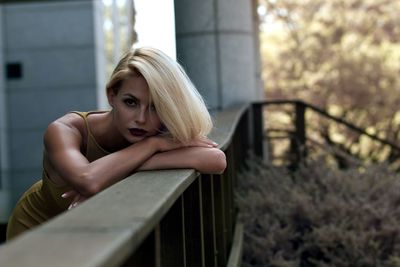 Beautiful fashion model leaning on wooden railing