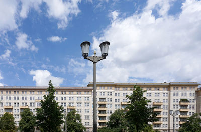 Low angle view of street light by building against sky