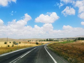 Road amidst field against sky