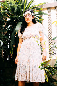 Portrait of young woman standing against plants