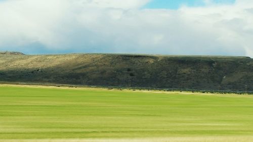 Scenic view of grassy field against cloudy sky