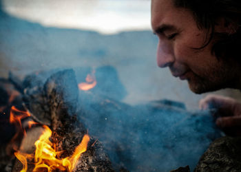 Close-up of man burning campfire outdoors