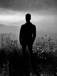 Rear view of silhouette man standing on field against sky