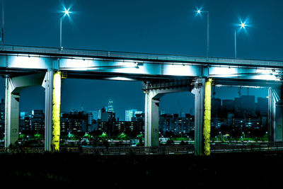 Illuminated bridge in city against sky at night