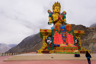 Statue of buddha against mountain range against sky