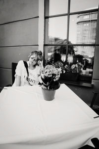 Woman sitting by potted plant on table in restaurant