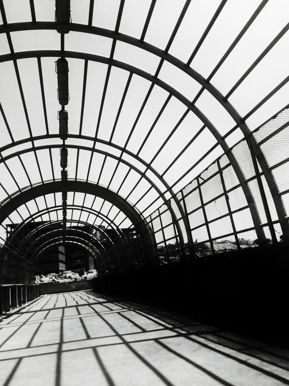 railroad track, indoors, built structure, architecture, rail transportation, transportation, railroad station, the way forward, ceiling, diminishing perspective, railroad station platform, public transportation, sky, railing, arch, day, sunlight, vanishing point, pattern, no people