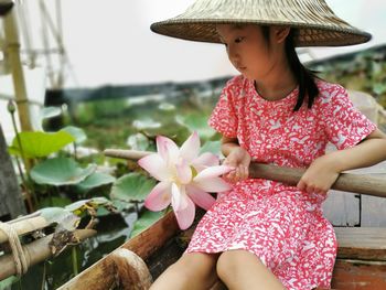 Girl holding wood while sitting in boat