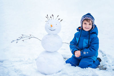 Portrait of cute boy with snowman 
