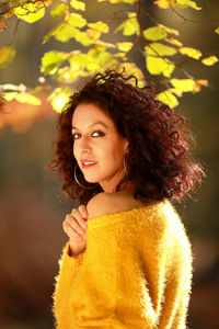 Portrait of young woman standing against tree