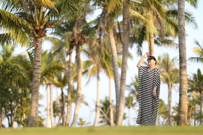 Woman standing on grass against palm trees
