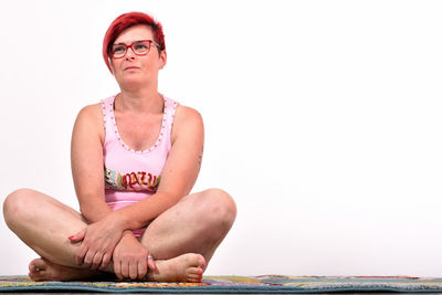 Portrait of young woman sitting against sea against sky