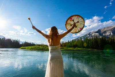 Woman standing by lake against sky