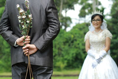 Man holding woman standing against plants