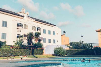 Buildings by swimming pool against sky