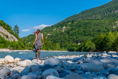 Rear view of woman standing on rocks against sky