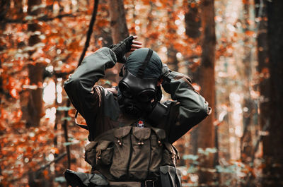 Rear view of man photographing in forest