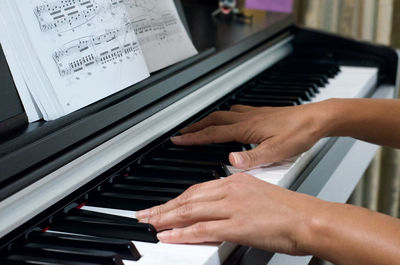 Cropped hands of woman playing piano