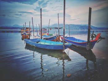 Fishing boats moored in sea against sky