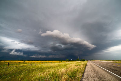 Scenic view of field against storm clouds