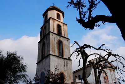 Low angle view of trees and building against sky