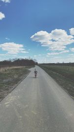 Man riding bicycle on road against sky