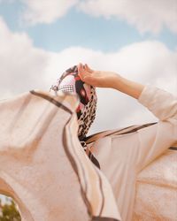 Low section of woman holding umbrella against sky