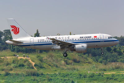 Airplane flying over land against sky