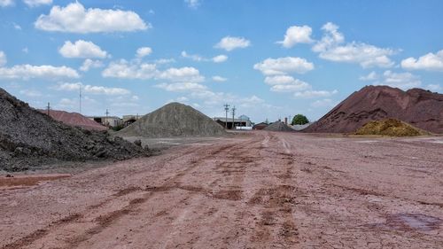 Dirt road at open-pit mine against sky