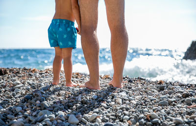 Low section of man with son standing at beach