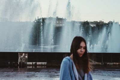 Portrait of woman by waterfall against sky