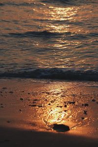 Surface level of beach against sky during sunset