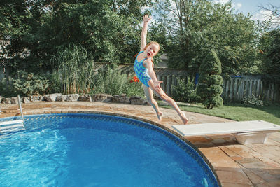 Full length of cute girl jumping in swimming pool