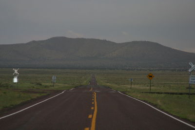 Road leading towards mountains against sky