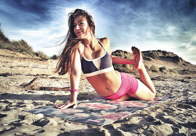 Young woman in bikini on beach against sky