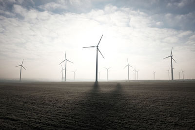 Wind turbines on landscape against sky