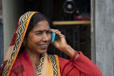 Close-up of smiling woman wearing sari talking over mobile phone